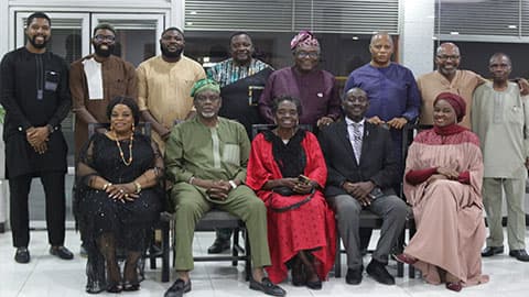 A group of thirteen alumni standing together and smiling at a dinner in Lagos, Nigeria.